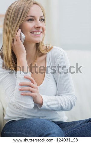 Casual young woman using mobile phone while sitting on couch at home