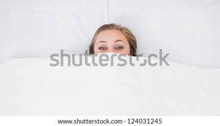 Woman hiding under the duvet in the bed