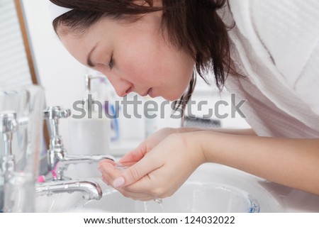 Close-up side view of young woman washing face