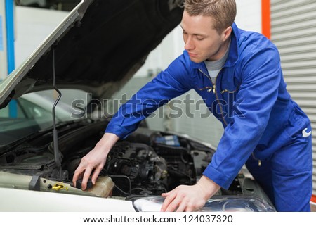 Portrait of male mechanic closing the lid of windshield washer tank