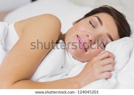 Content woman asleep in bed in hotel room