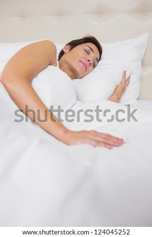 Peaceful woman asleep in bed in hotel room