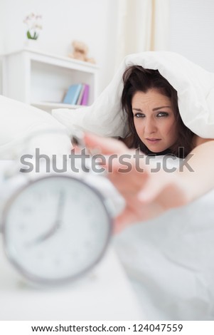 Close-up of woman in bed extending hand to alarm clock
