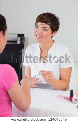 Nail technician applying nail varnish to finger nails at nail salon