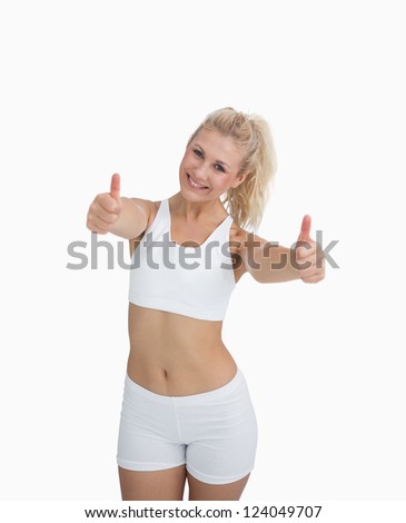 Portrait of happy young woman in sportswear giving thumbs up over white background