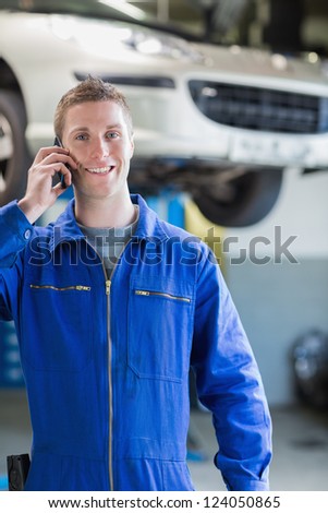 Portrait of young male car mechanic using mobile phone