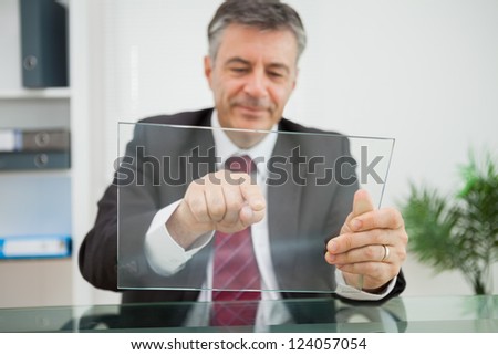 Happy man pointing on his virtual screen on his desk in his office