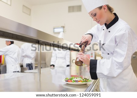 Chef seasoning salad with pepper in kitchen