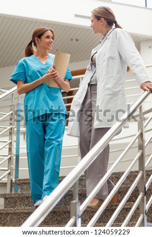 Female doctor talking to an intern in a hospital\'s stairs