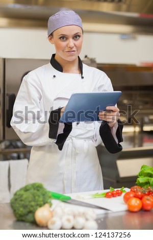 Chef using digital tablet and smiling in the kitchen
