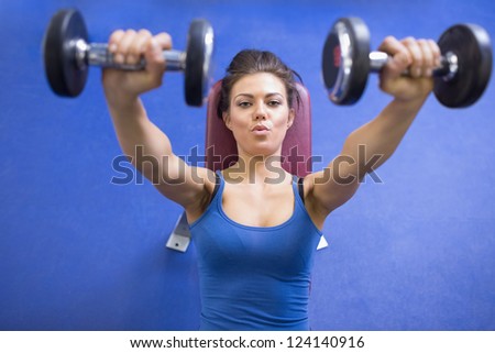 Black-haired woman energetically lifting weights