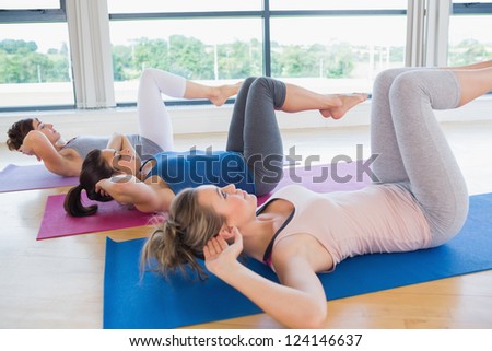 Women doing core exercise on mats in fitness studio