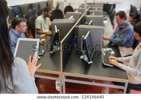 Woman holding a tablet pc while teaching her computer class