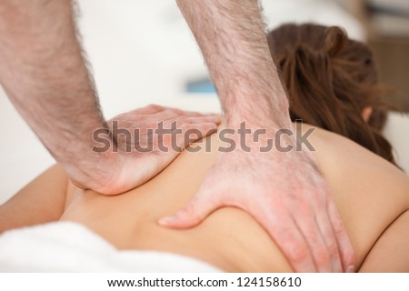 Woman lying on the belly while being massaging with two hands of doctor indoors