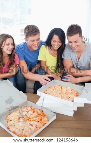 A group of friends with some pizza as one guy reaches out for a slice