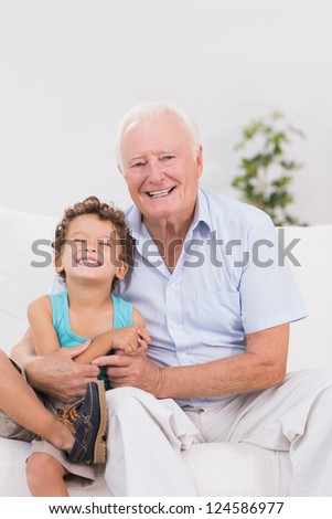 Grandfather and grandson sitting on the sofa while smiling