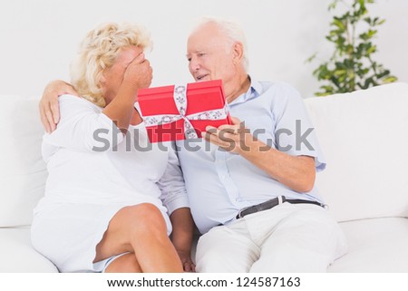 Old man offering a gift to the elderly woman on the sofa