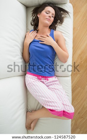 Woman in pyjamas asleeps on sofa in living room