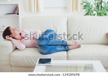 Casual young woman resting on  couch with digital tablet on table