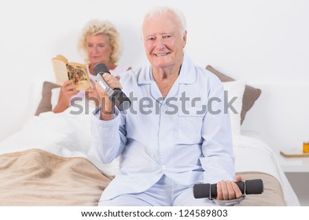 Elderly man lifting hand weights in the bedroom
