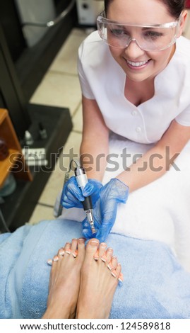 Nail technician removing callus at feet in nail salon