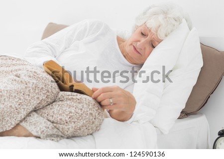 Old woman lying on the bed and reading a old novel