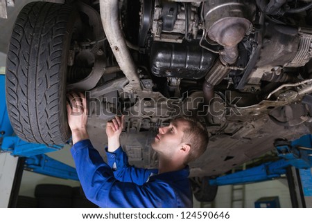 Male mechanic under car in garage