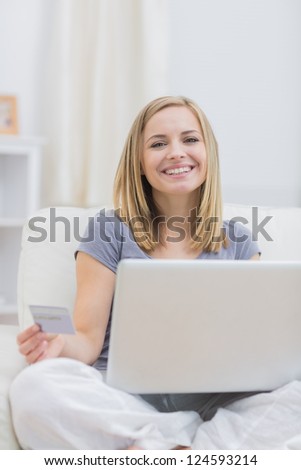 Portrait of casual young woman doing online shopping on couch at home