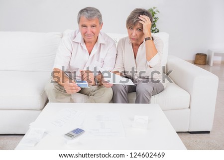 Old stressed couple calculating bills in sitting room