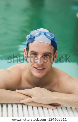 Happy man wearing goggles and cap in swimming pool