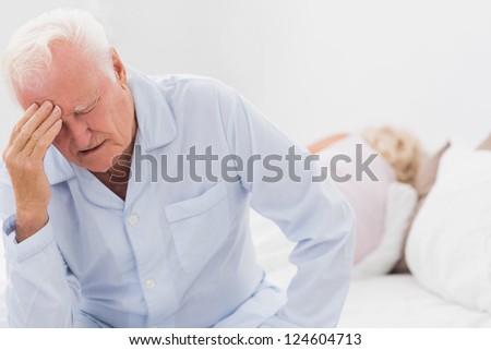Old man suffering while woman sleeping on the bed