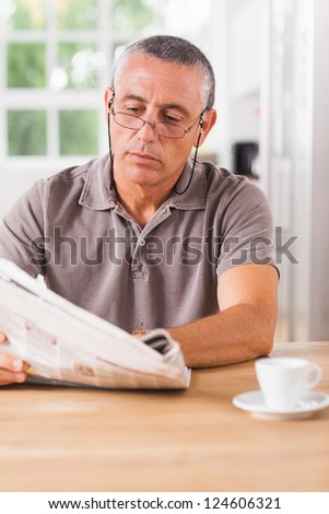 Man reading newspaper at kitchen table