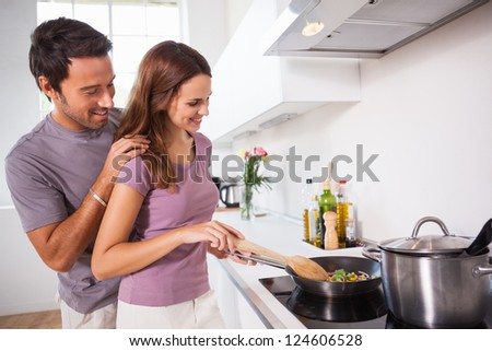 Woman making dinner with partner watching in kitchen