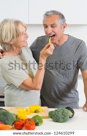 Husband tasting a slice of yellow pepper in the kitchen