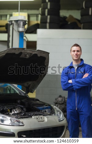 Portrait of confident male mechanic standing by car with open hood