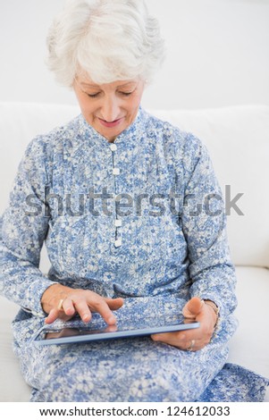 Elderly focused woman using a digital tablet on a sofa