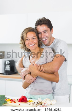 Husband hugging wife at the chopping board in the kitchen