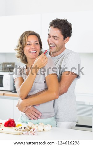 Wife Jokingly Feeding Husband Slice Of Pepper In The Kitchen St image