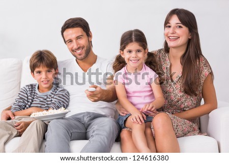 Smiling family watching the television together on the couch