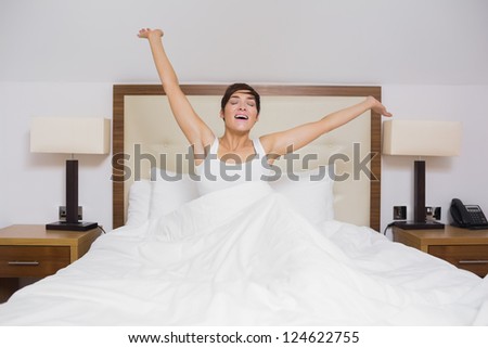 Pretty woman waking up in hotel room and stretching