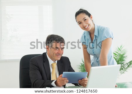 Business man and woman smiling together in an office while working