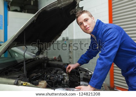 Portrait of confident male mechanic checking car engine oil