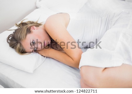 Blonde woman thinking in the bed in the white background