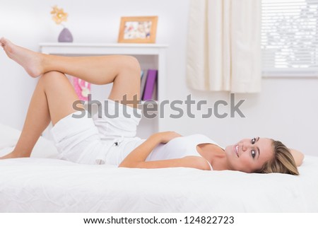 Cheerful blond woman lying on her bed in the white bedroom