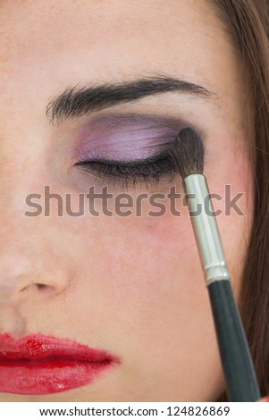 Brunette with red lips getting eye shadow applied