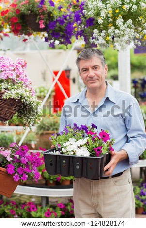 Smiling customer taking flower boxes outside in garden center