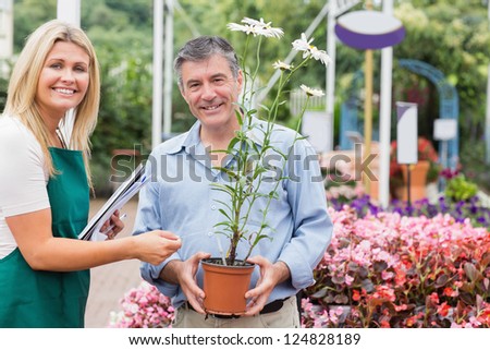 Gardener giving advice to customer while holding a flower and smiling