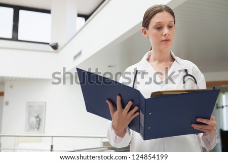 Female doctor reading  folder in hospital corridor