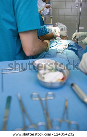 Group of surgeons working next to a surgical trolley in an operating theater