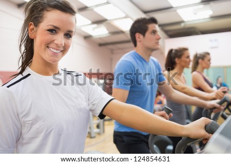Smiling brunette with other people on a step machine in gym